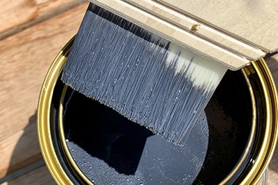 ペンキをつけた筆で木材を塗装